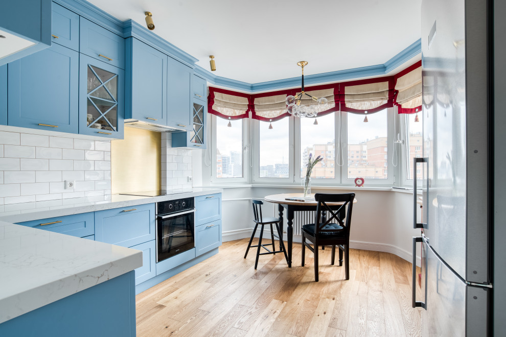 Пример оригинального дизайна: отдельная, угловая кухня среднего размера в стиле неоклассика (современная классика) с синими фасадами, столешницей из кварцевого агломерата, белой столешницей и красивой плиткой