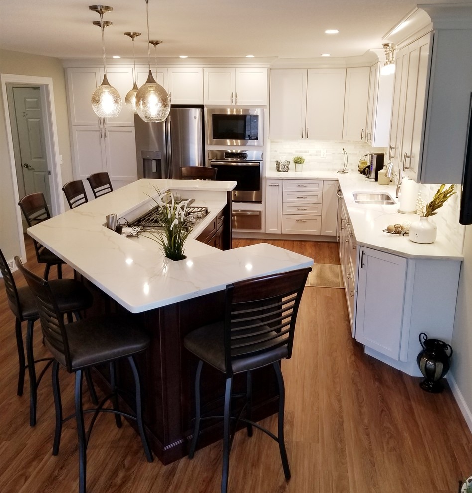 Example of a large transitional l-shaped medium tone wood floor and brown floor open concept kitchen design in Chicago with shaker cabinets, white cabinets, quartzite countertops, white backsplash, an island, a double-bowl sink and stainless steel appliances