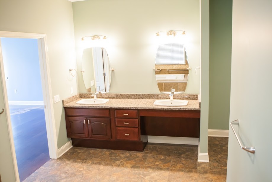 This is an example of a mid-sized traditional bathroom in Other with raised-panel cabinets, dark wood cabinets, green walls, linoleum floors, a drop-in sink and brown floor.