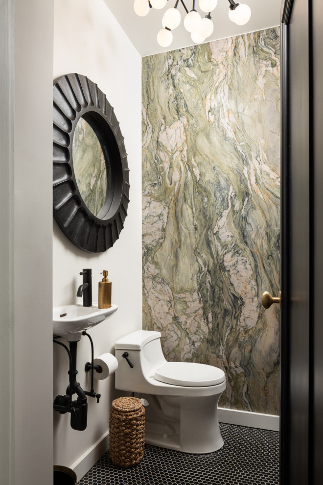 This is an example of a small transitional powder room in New York with white cabinets, a one-piece toilet, stone slab, grey walls, a wall-mount sink and black floor.