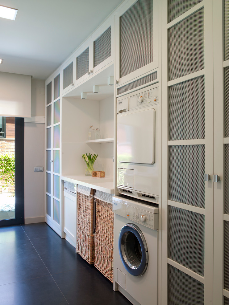 This is an example of a large contemporary dedicated laundry room in Barcelona with a stacked washer and dryer.