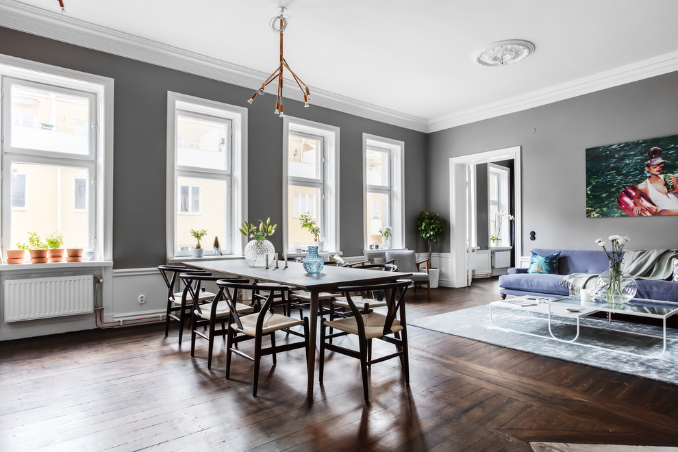 На фото: большая столовая в скандинавском стиле с серыми стенами, темным паркетным полом и коричневым полом