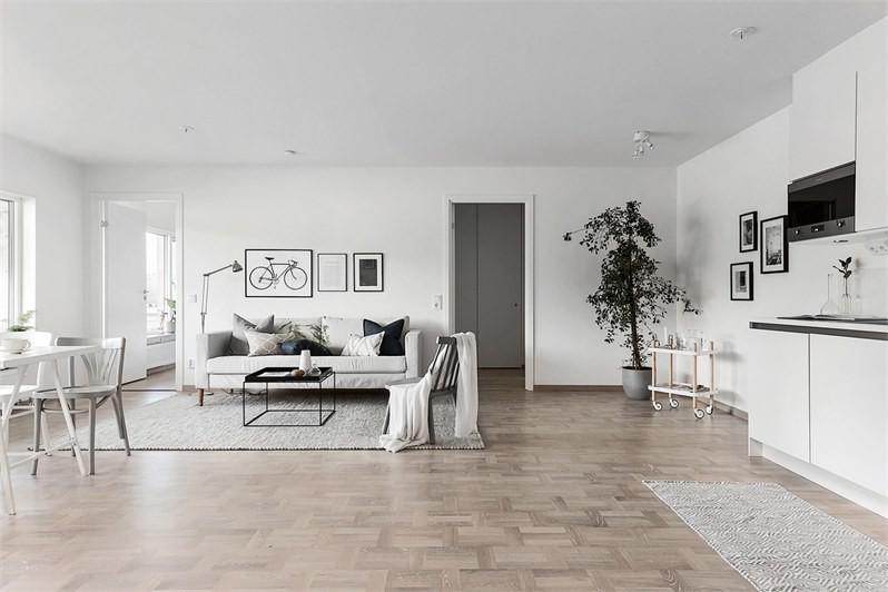 Inredning av ett minimalistiskt mellanstort allrum med öppen planlösning, med vita väggar, mellanmörkt trägolv och beiget golv