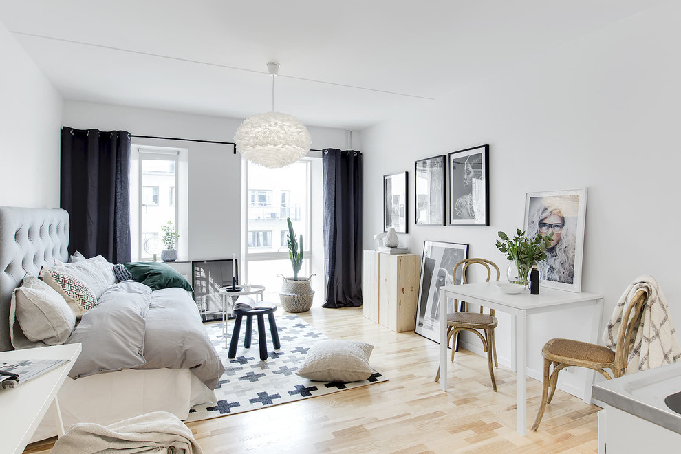 На фото: открытая гостиная комната в скандинавском стиле с белыми стенами и светлым паркетным полом с
