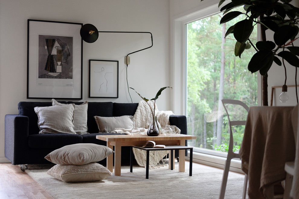 Diseño de sala de estar nórdica con paredes blancas, suelo de madera clara y suelo beige