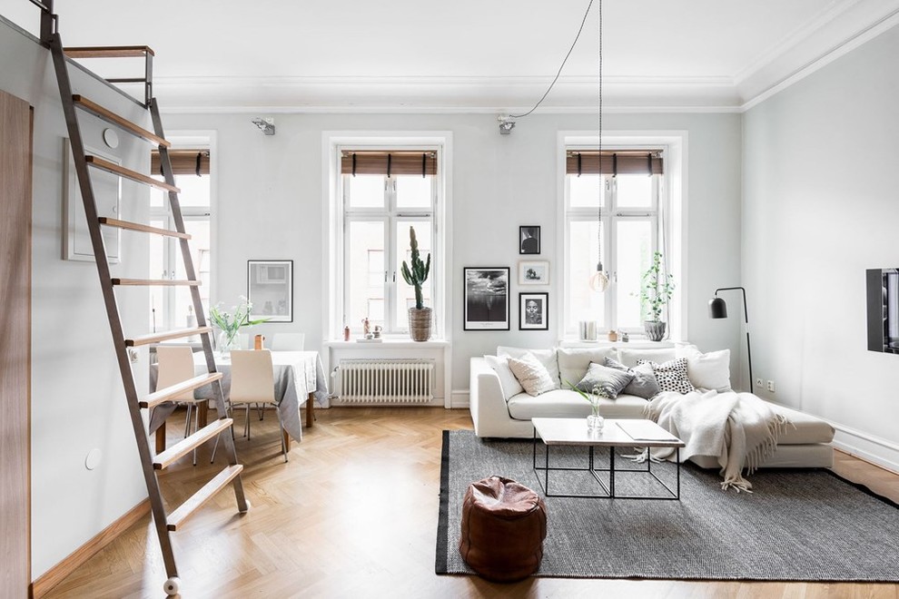 Immagine di un soggiorno scandinavo aperto e di medie dimensioni con pareti grigie, pavimento in legno massello medio e nessuna TV