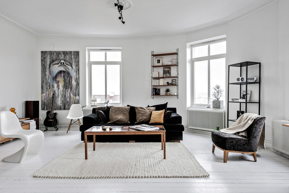 Nordisk inredning av ett stort allrum, med vita väggar, målat trägolv och vitt golv