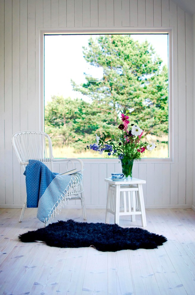Exemple d'une salle de séjour nature avec un mur blanc, parquet clair, un poêle à bois, un manteau de cheminée en métal et un sol blanc.