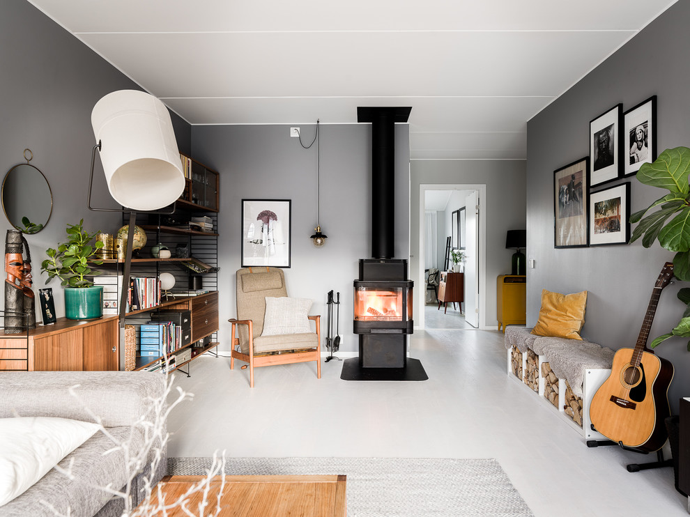 Diseño de sala de estar cerrada escandinava de tamaño medio con paredes grises, suelo laminado, estufa de leña, marco de chimenea de metal y suelo gris