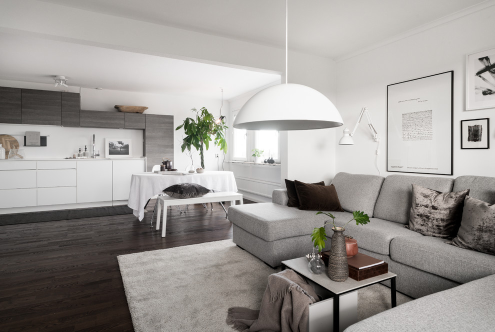 Mittelgroßes, Offenes Nordisches Wohnzimmer mit weißer Wandfarbe, dunklem Holzboden und schwarzem Boden in Stockholm