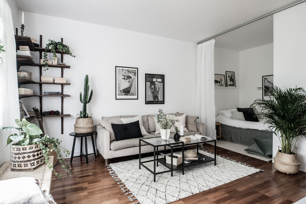 Идея дизайна: гостиная комната в скандинавском стиле с белыми стенами, темным паркетным полом и коричневым полом