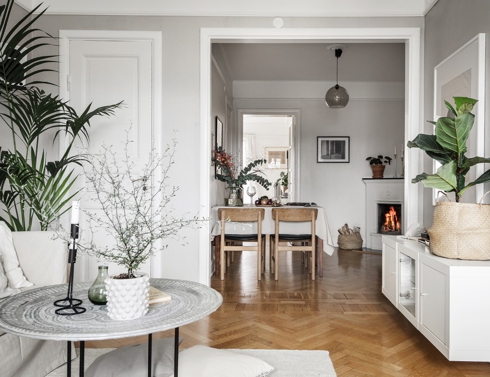 Idéer för mellanstora skandinaviska allrum med öppen planlösning, med grå väggar, mellanmörkt trägolv, en öppen hörnspis och en spiselkrans i gips