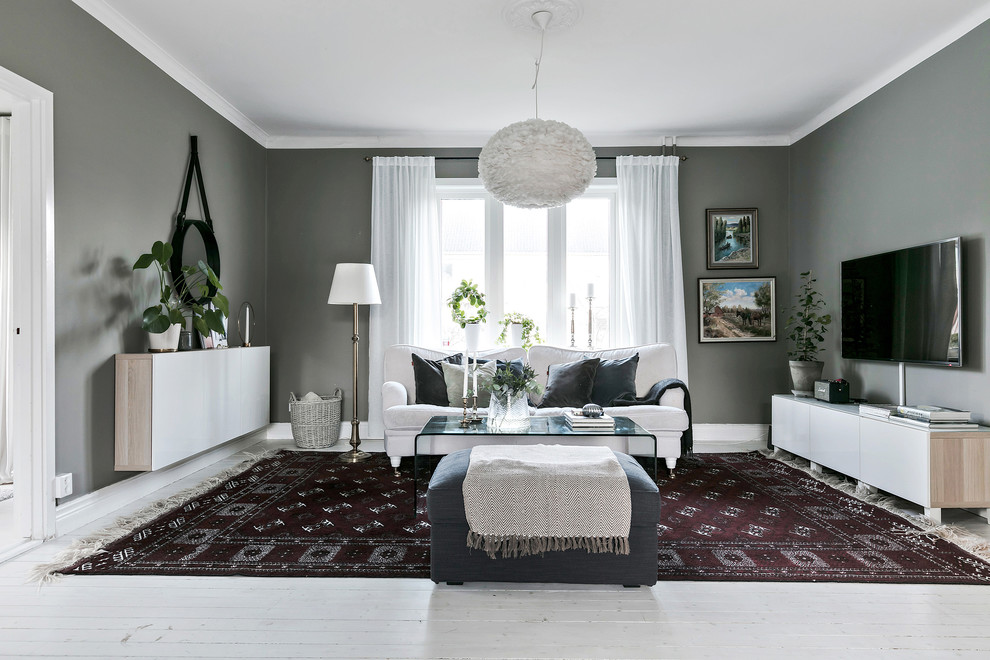Идея дизайна: изолированная гостиная комната в скандинавском стиле с серыми стенами, деревянным полом, белым полом и телевизором на стене