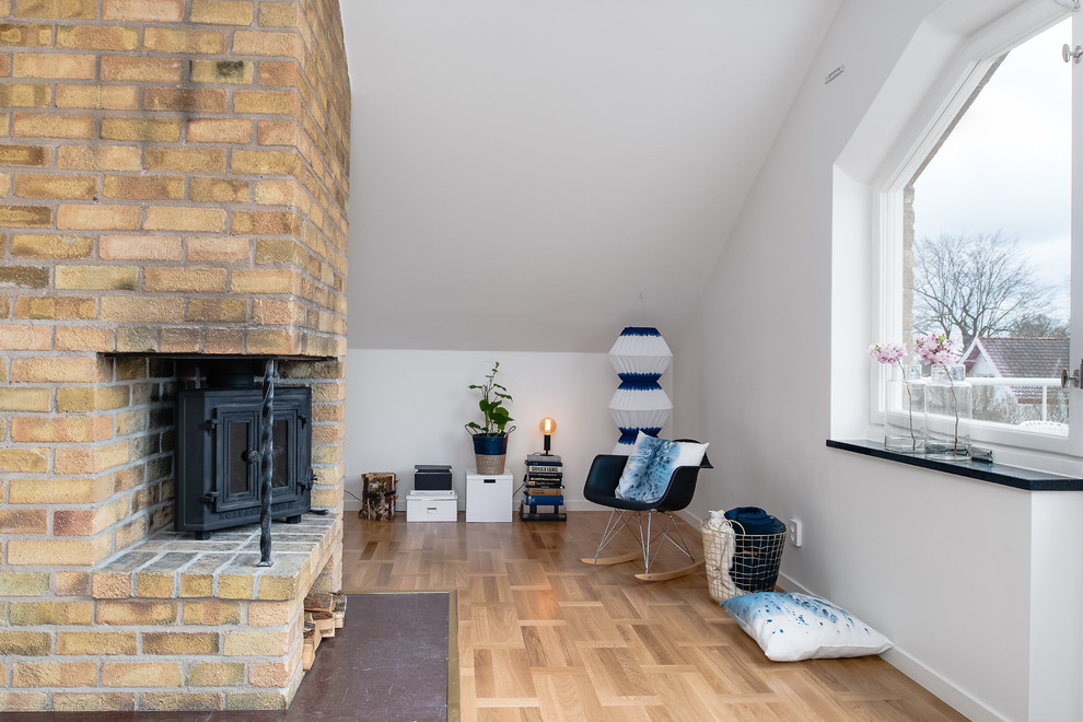 Foto de sala de estar abierta escandinava de tamaño medio sin televisor con paredes blancas, suelo de madera clara y chimenea de esquina
