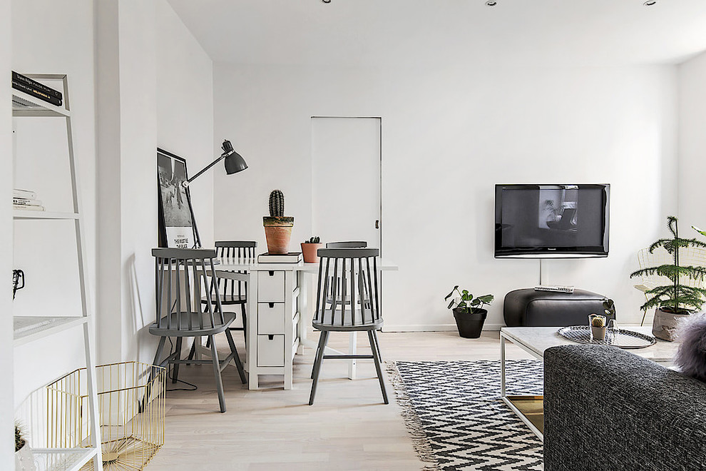 This is an example of a small scandinavian enclosed games room in Stockholm with white walls, light hardwood flooring and a wall mounted tv.