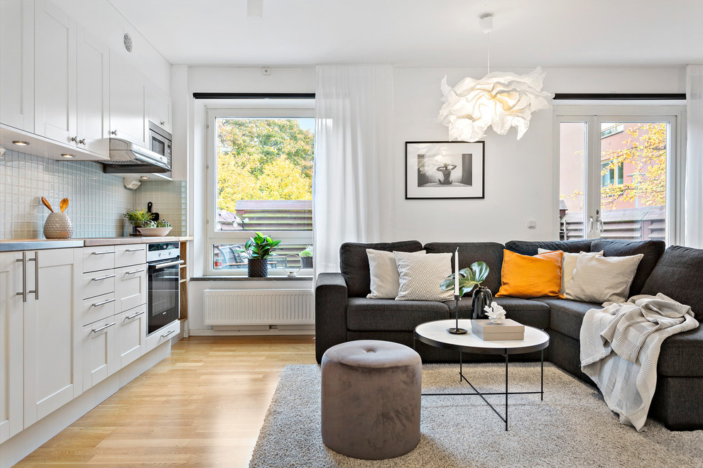 This is an example of a small traditional open plan games room in Stockholm with white walls, light hardwood flooring and beige floors.