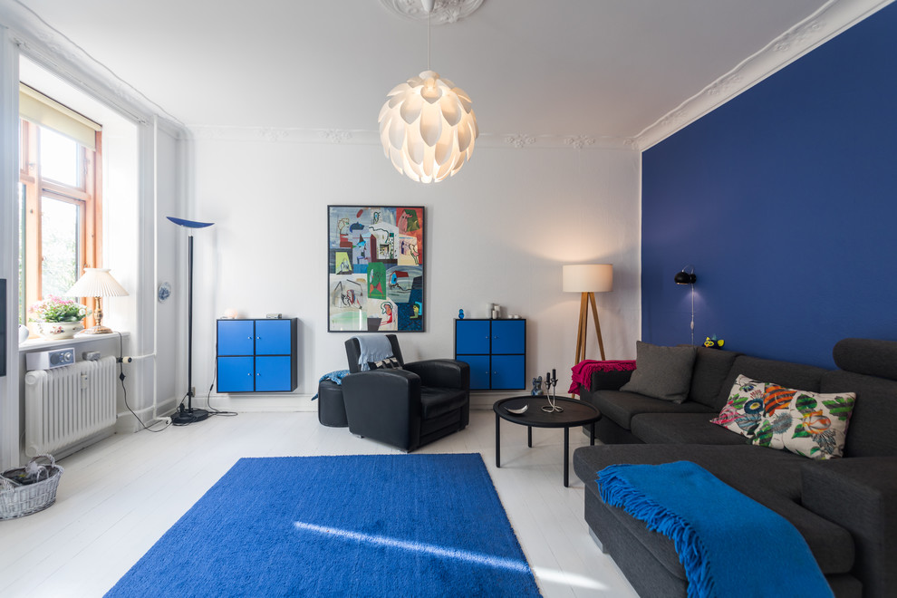Aménagement d'une salle de séjour scandinave de taille moyenne et fermée avec un mur multicolore, parquet peint, un sol blanc et canapé noir.