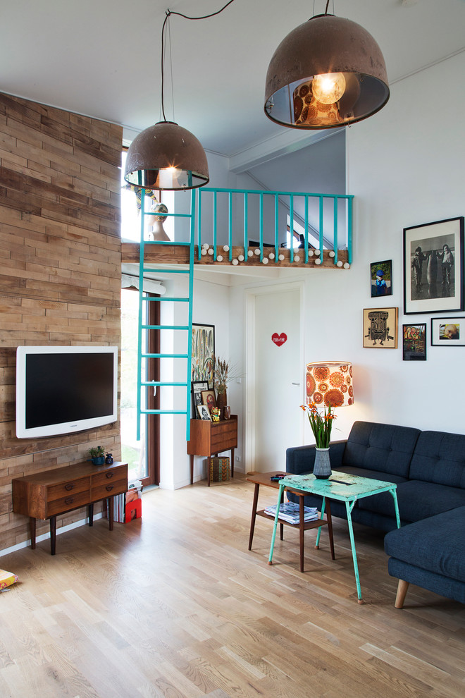 Diseño de sala de estar abierta nórdica pequeña sin chimenea con paredes blancas, suelo de madera clara y televisor colgado en la pared