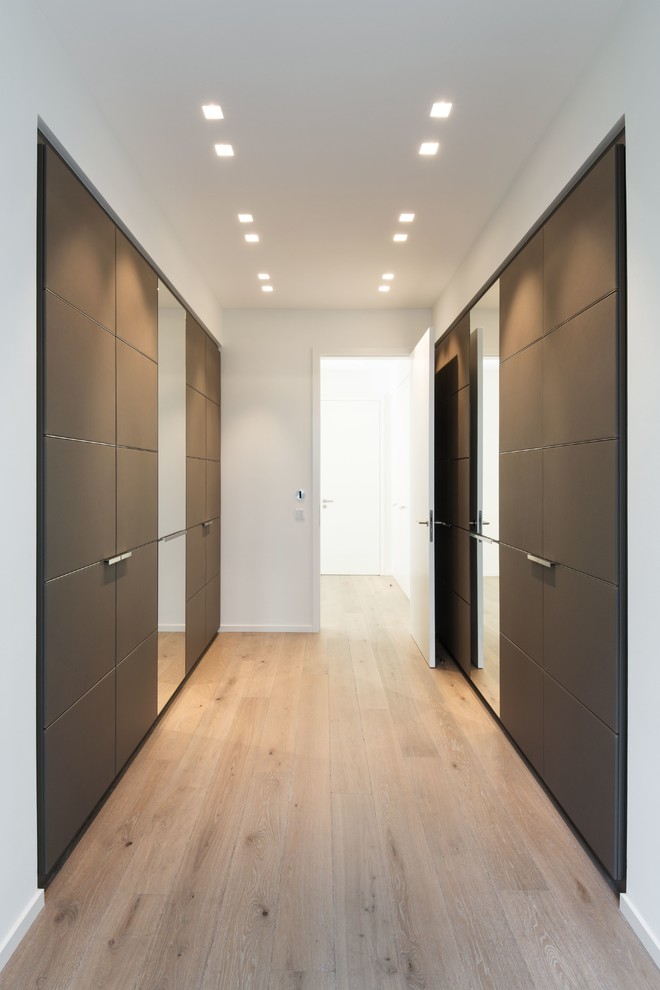 Idées déco pour un très grand placard dressing contemporain neutre avec un placard à porte affleurante et des portes de placard marrons.