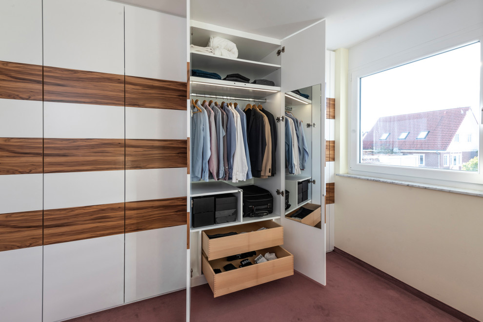 Photo of a contemporary walk-in wardrobe in Stuttgart with flat-panel cabinets, white cabinets, carpet and red floors.