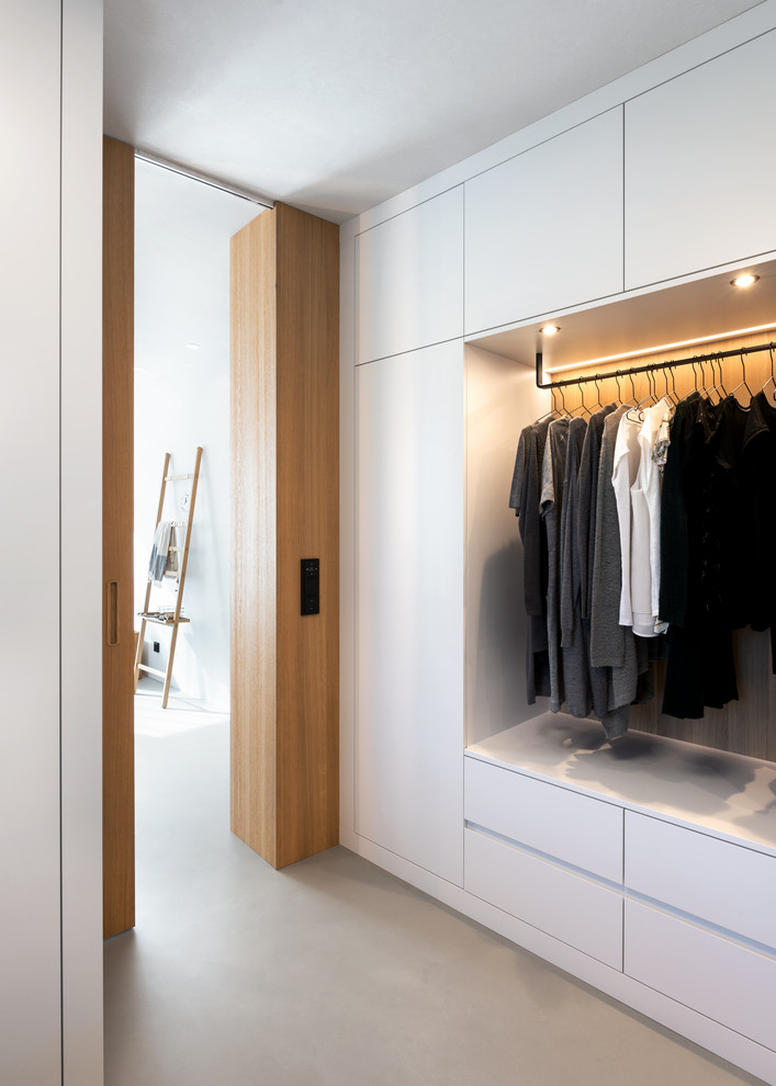 Imagen de armario vestidor unisex escandinavo con armarios con paneles lisos, puertas de armario blancas, suelo de cemento y suelo gris
