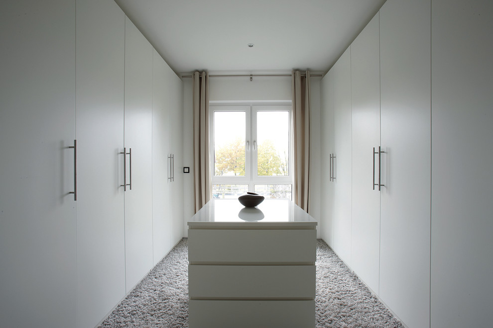 На фото: большая гардеробная комната унисекс в современном стиле с плоскими фасадами, белыми фасадами, ковровым покрытием и серым полом