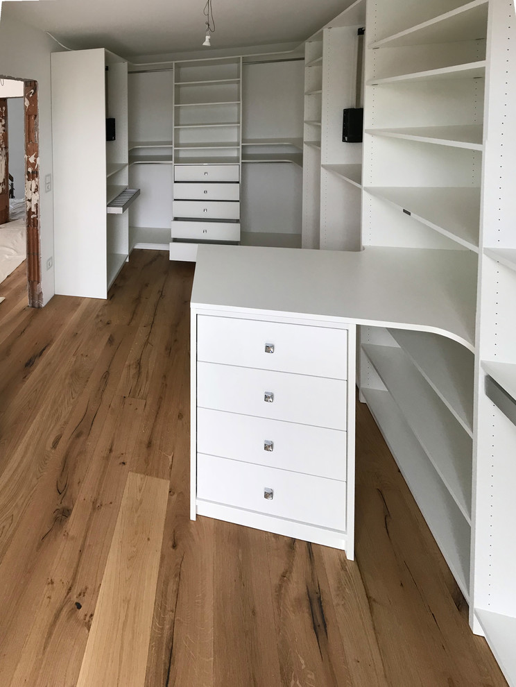 This is an example of a medium sized contemporary gender neutral walk-in wardrobe in Other with open cabinets, white cabinets, painted wood flooring and beige floors.