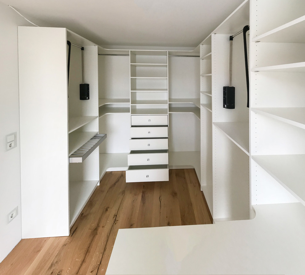 Modelo de armario vestidor unisex contemporáneo de tamaño medio con armarios abiertos, puertas de armario blancas, suelo de madera pintada y suelo beige