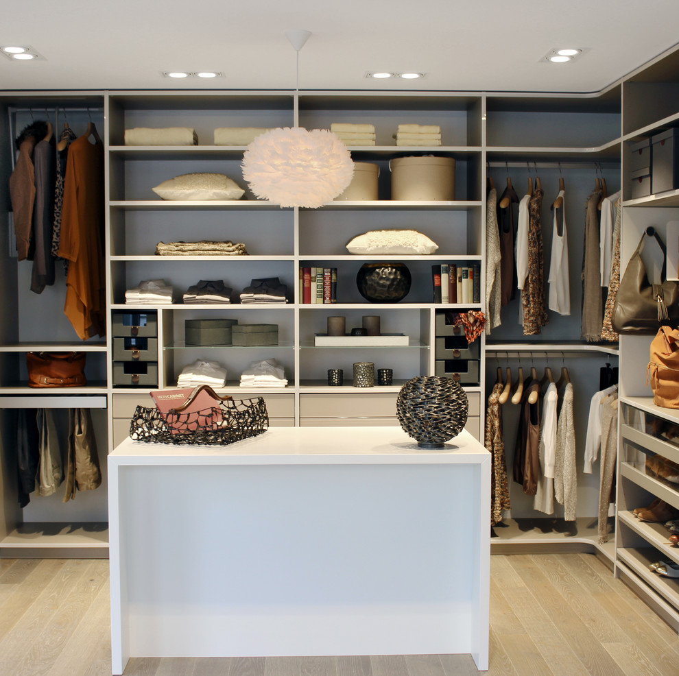 Diseño de armario vestidor unisex clásico de tamaño medio con armarios abiertos, puertas de armario blancas, suelo de madera clara y suelo beige