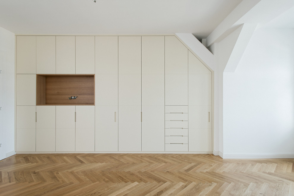Geräumiges, Neutrales Modernes Ankleidezimmer mit Ankleidebereich, flächenbündigen Schrankfronten, beigen Schränken, hellem Holzboden und beigem Boden in München