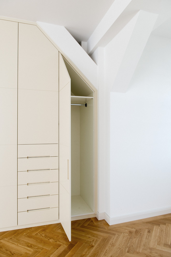 Idee per un ampio spazio per vestirsi unisex minimal con ante lisce, ante beige, pavimento marrone e pavimento in legno massello medio