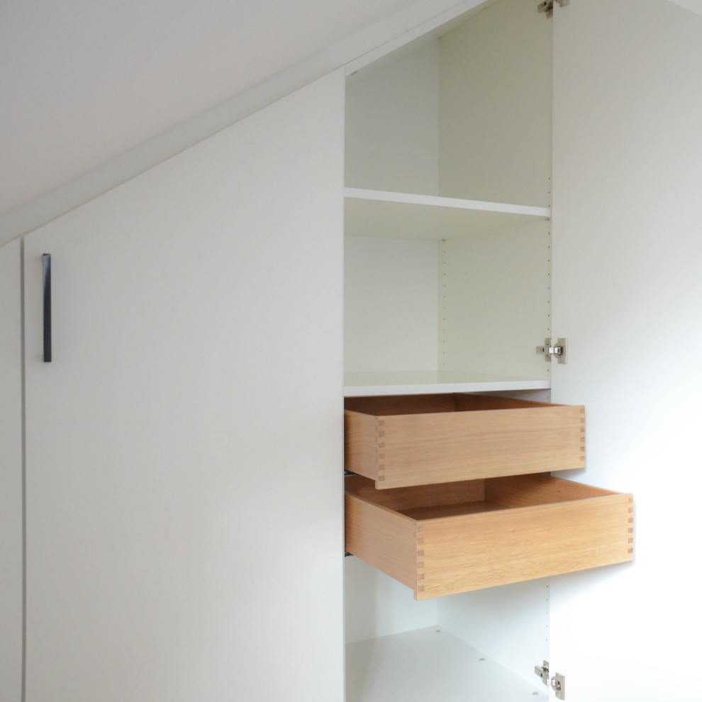 Esempio di un armadio o armadio a muro minimalista con ante bianche, parquet chiaro e pavimento marrone