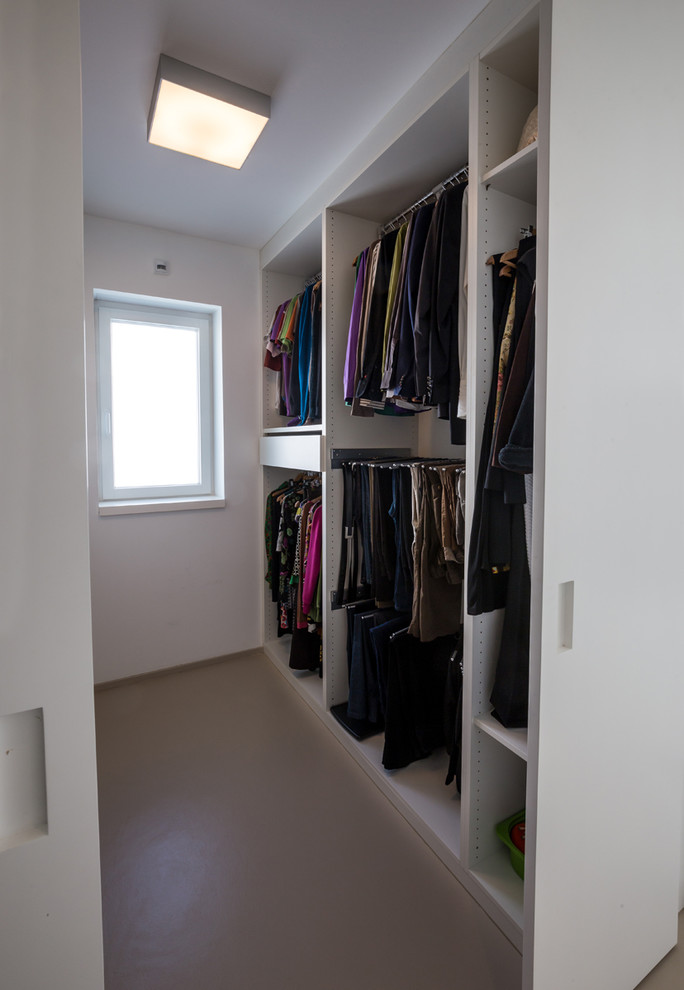 Immagine di una piccola cabina armadio unisex design con nessun'anta, pavimento in cemento e pavimento grigio