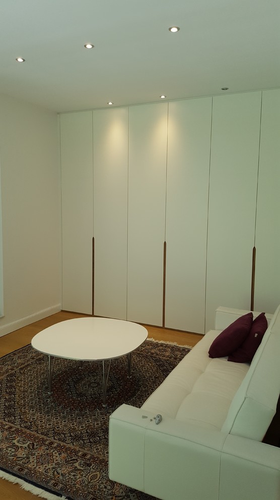 Ejemplo de vestidor unisex contemporáneo de tamaño medio con armarios con paneles lisos, puertas de armario blancas, suelo laminado y suelo marrón