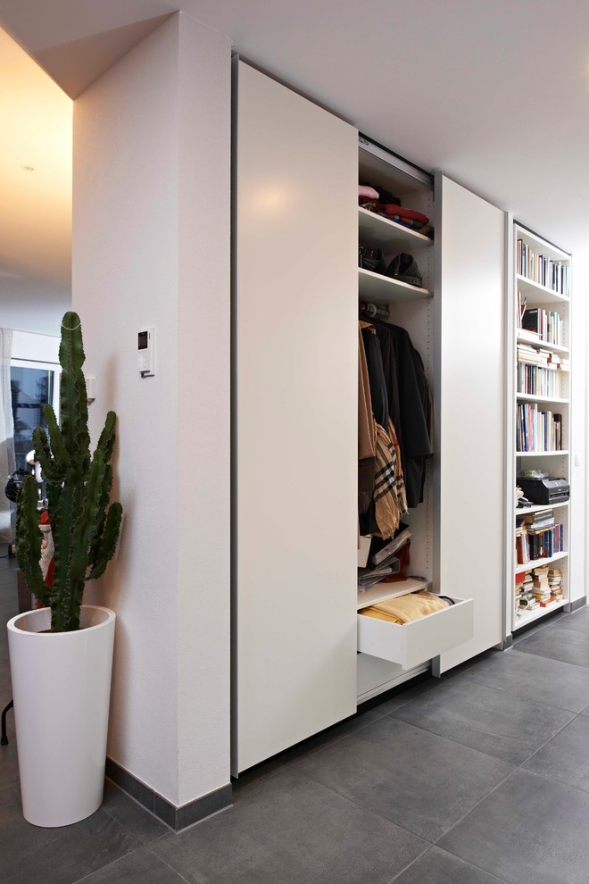 Esempio di un armadio o armadio a muro unisex design con ante lisce, ante bianche e pavimento grigio
