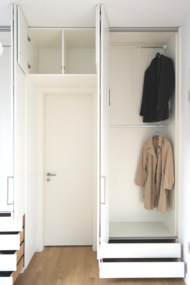 Foto de armario moderno con armarios con paneles lisos, puertas de armario blancas y suelo de madera en tonos medios