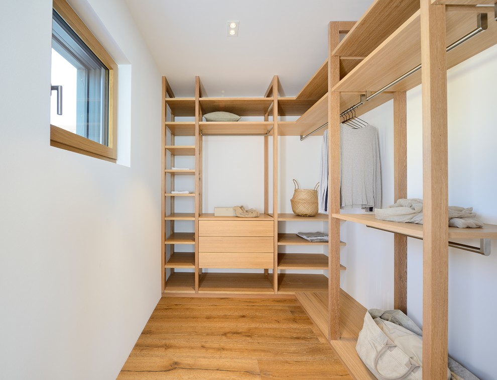 Ejemplo de armario vestidor unisex nórdico de tamaño medio con armarios abiertos, suelo de madera oscura y puertas de armario beige