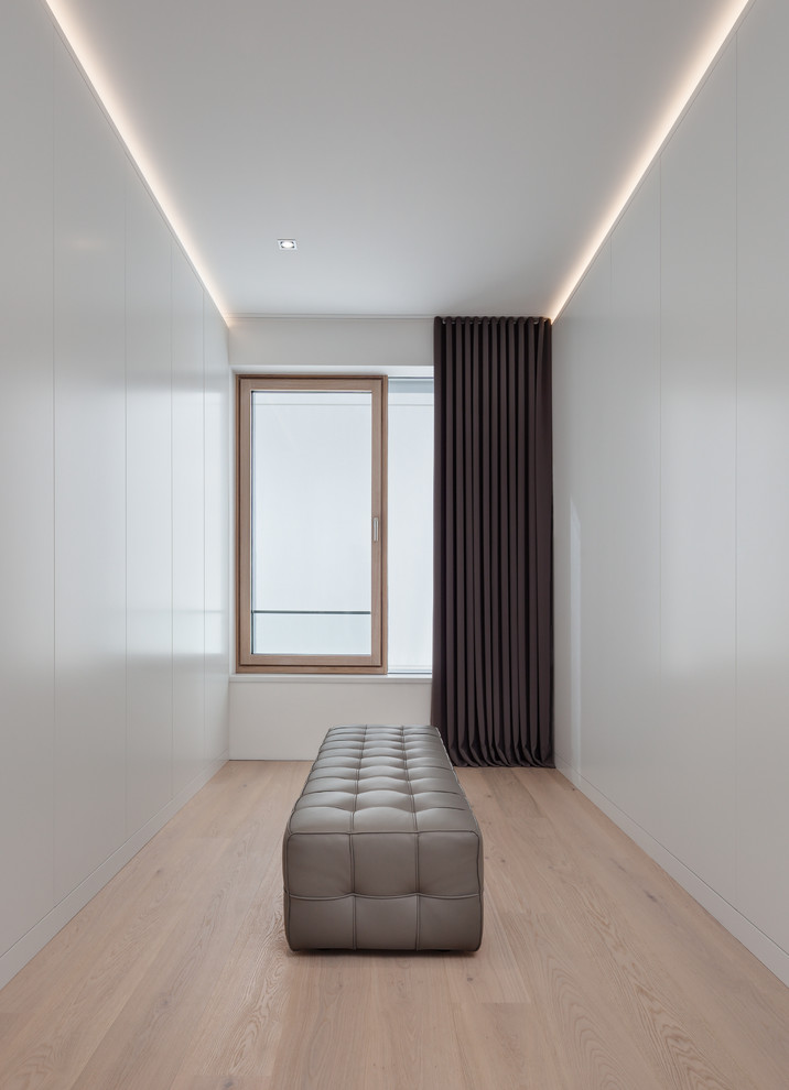 Foto di uno spazio per vestirsi unisex moderno di medie dimensioni con ante lisce, ante bianche, parquet chiaro e pavimento beige
