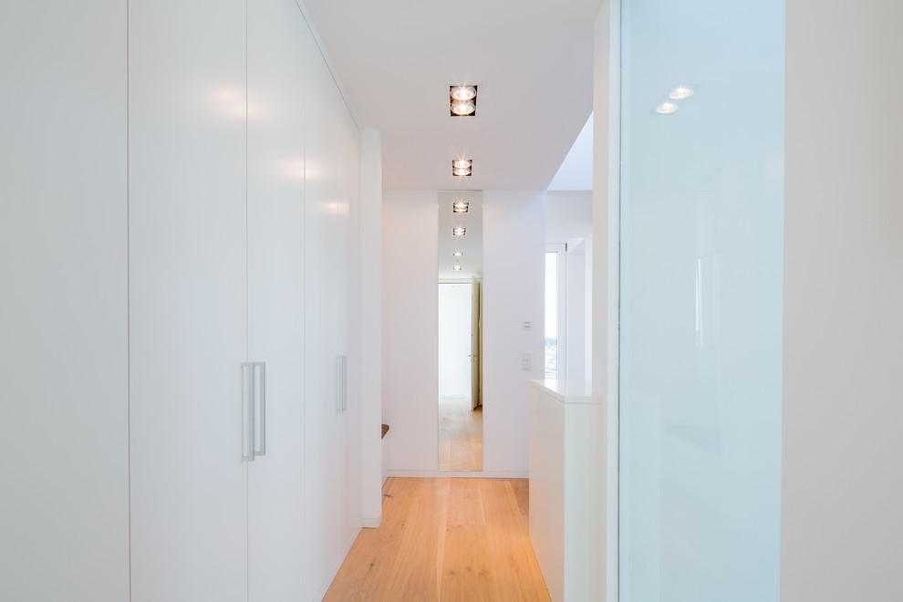 Esempio di uno spazio per vestirsi unisex moderno di medie dimensioni con ante lisce, ante bianche, pavimento in legno massello medio e pavimento beige
