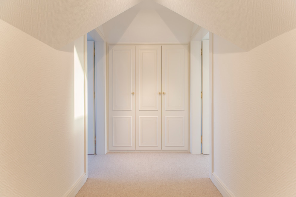 Пример оригинального дизайна: гардеробная комната среднего размера, унисекс в стиле неоклассика (современная классика) с ковровым покрытием и белыми фасадами