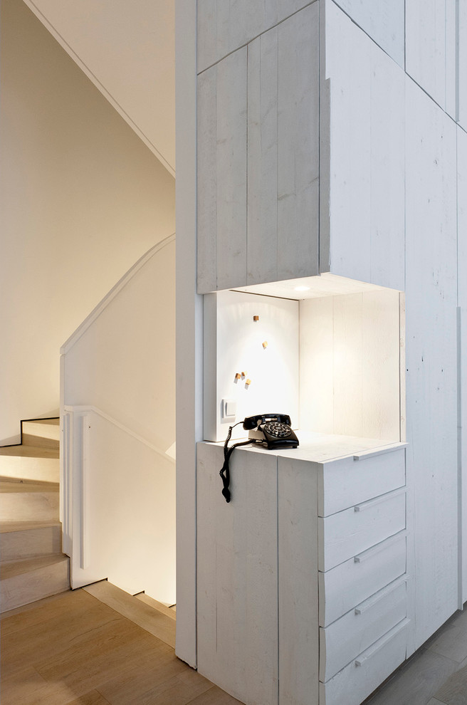 Foto på ett minimalistiskt omklädningsrum för könsneutrala, med vita skåp och mellanmörkt trägolv