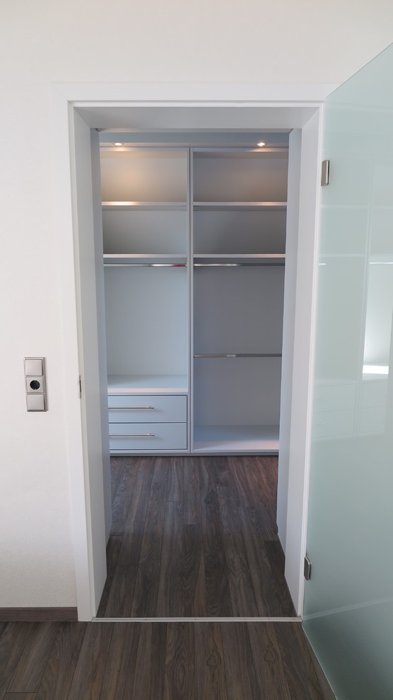 Foto de vestidor unisex actual de tamaño medio con armarios con paneles lisos, puertas de armario blancas y suelo laminado