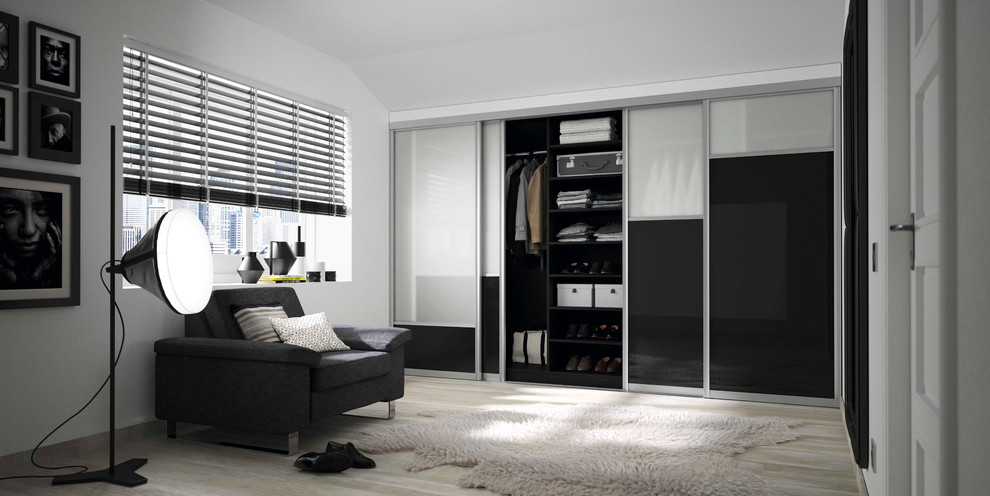 Large traditional standard wardrobe in Cologne with glass-front cabinets, black cabinets, light hardwood flooring and brown floors.