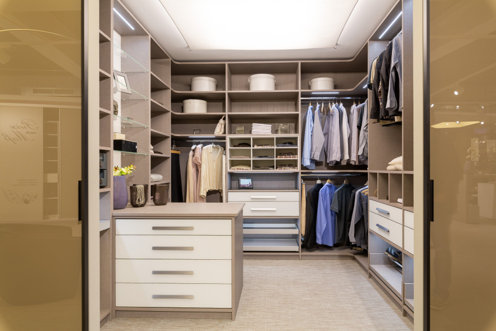 Diseño de armario vestidor unisex actual de tamaño medio con armarios con paneles lisos, puertas de armario beige, moqueta y suelo beige