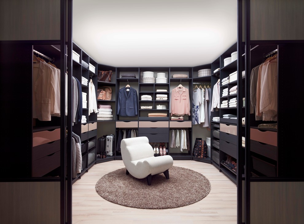 Diseño de armario vestidor unisex tradicional con puertas de armario negras, suelo de madera clara y armarios abiertos