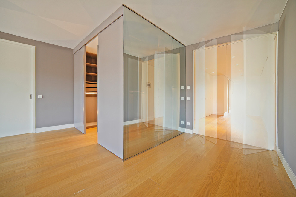 This is an example of a large contemporary gender neutral walk-in wardrobe in Munich with open cabinets and light hardwood flooring.