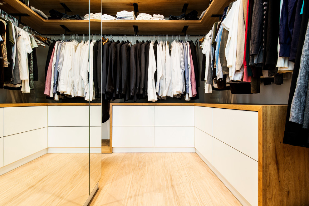 Ejemplo de armario vestidor de hombre contemporáneo de tamaño medio con puertas de armario blancas, suelo de madera clara, armarios con paneles lisos y suelo beige