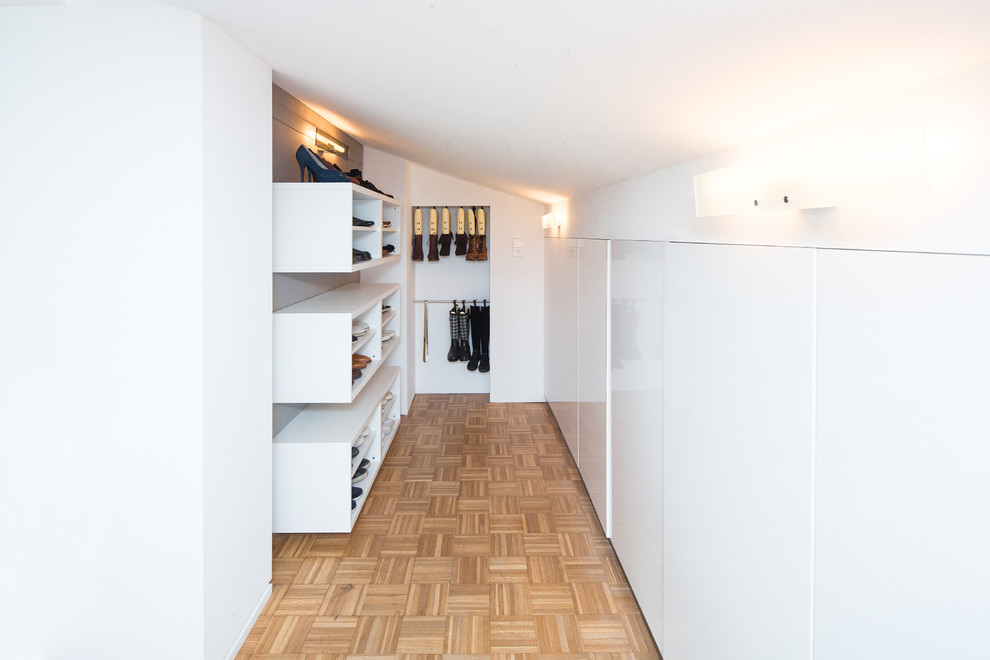 Modern inredning av ett litet walk-in-closet för könsneutrala, med öppna hyllor, vita skåp, mellanmörkt trägolv och beiget golv