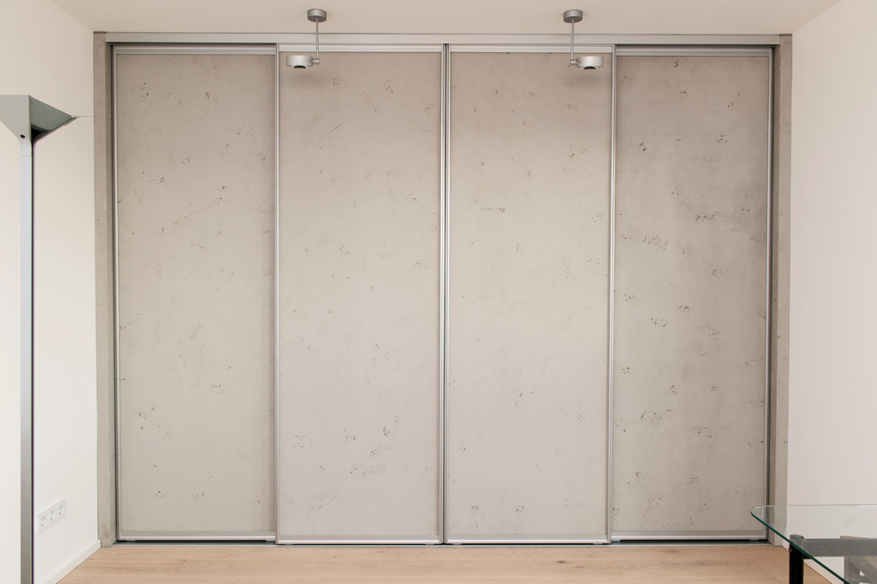 Inspiration pour un très grand dressing room design neutre avec un placard à porte plane, des portes de placard grises, parquet clair et un sol marron.