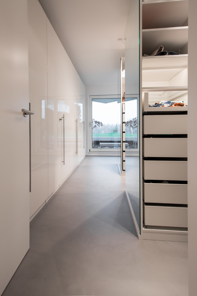 Idee per una grande cabina armadio unisex moderna con ante lisce, ante bianche, pavimento in cemento e pavimento grigio